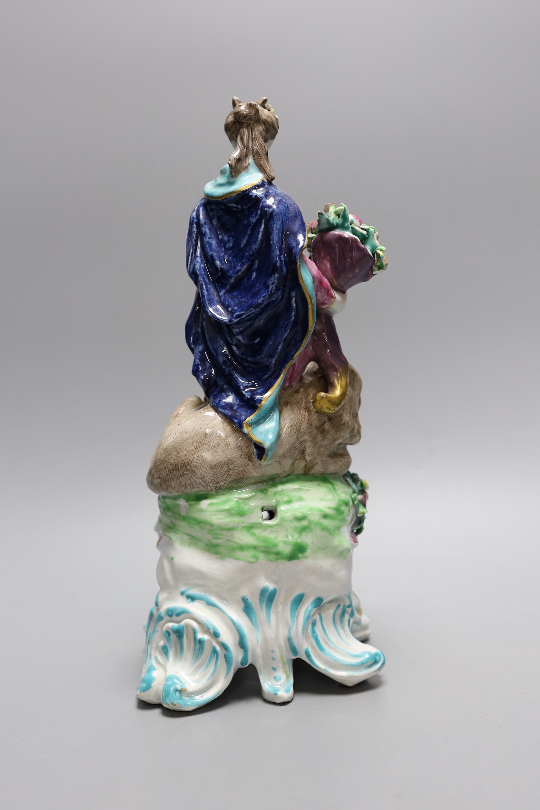 A Bow figure of Plenty, a caped woman sanding holding a cornucopia full of fruit beside a well modelled lion, c.1765, 28cm